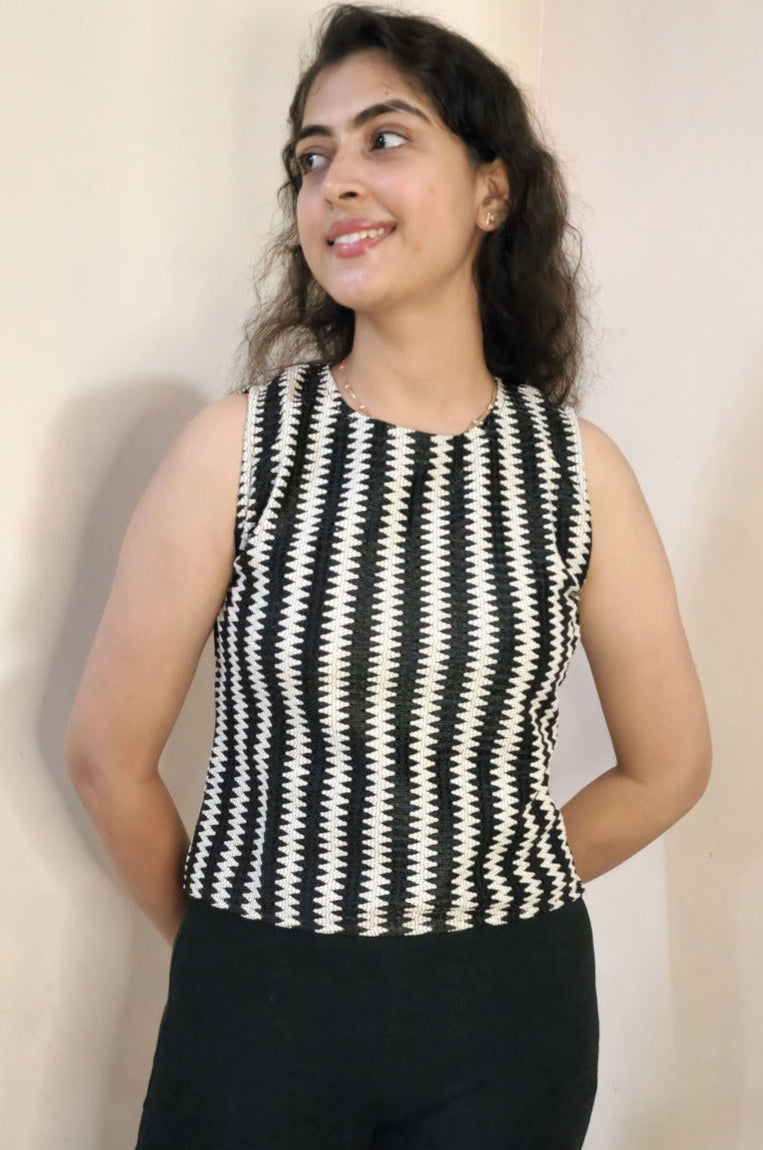 Woman wearing a black and white striped sleeveless top against a plain background