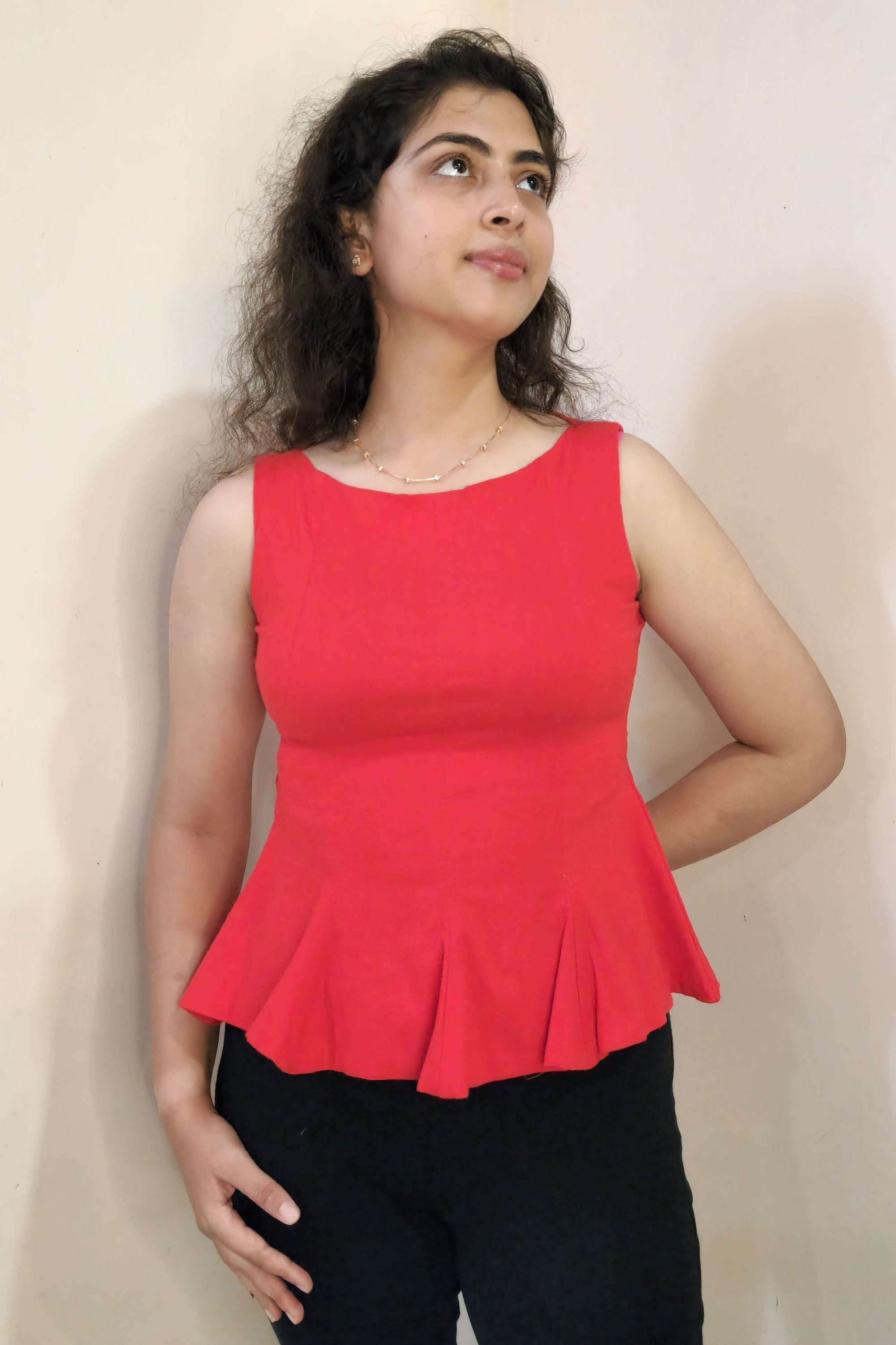 Woman wearing a red top and black pants on a plain background