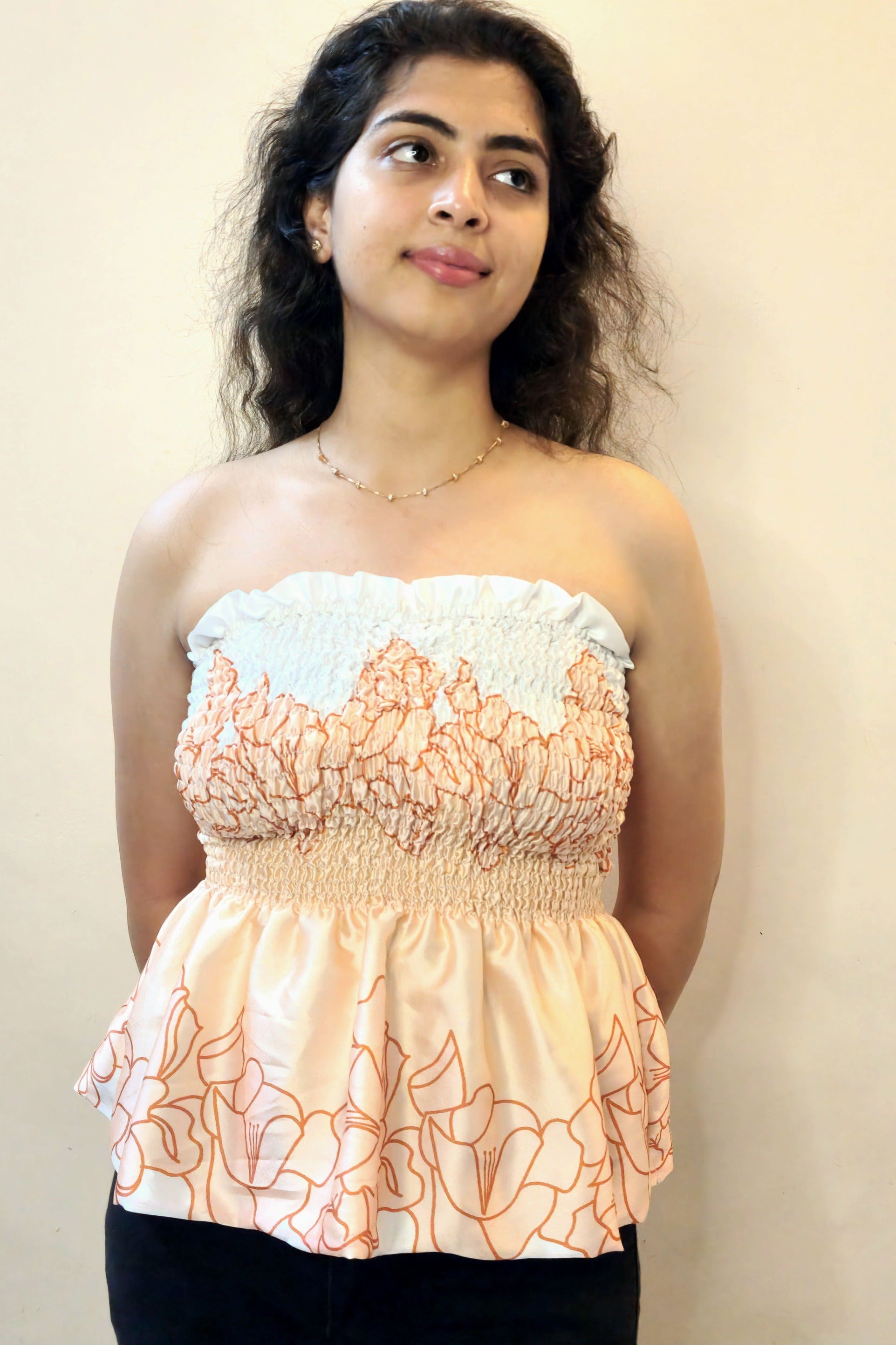 Woman wearing a floral strapless top against a plain background