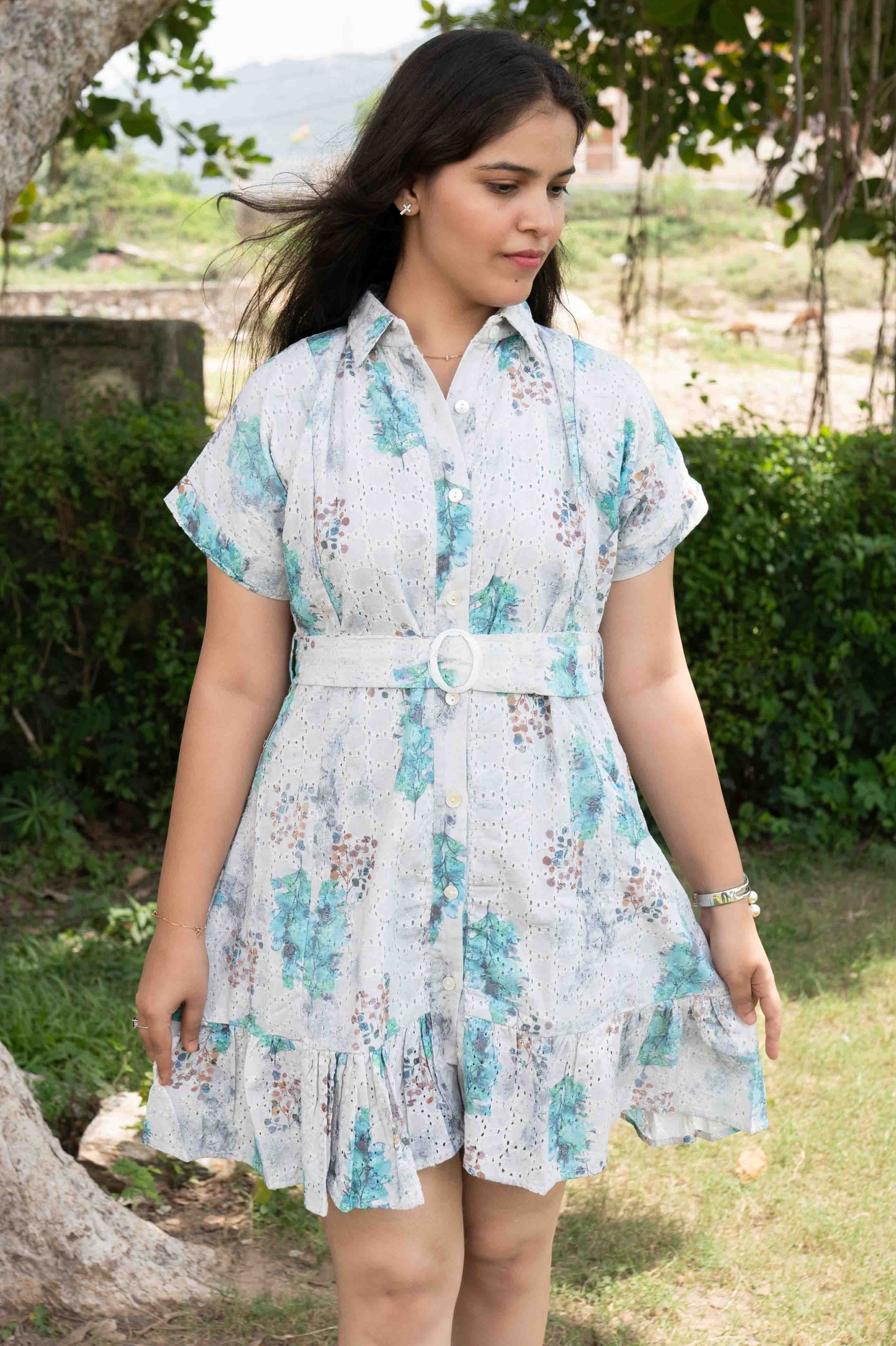 Woman wearing a floral dress standing outdoors near a tree