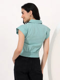 Woman wearing a light blue sleeveless blouse against a white background