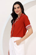 Woman wearing a red top with white trim against a neutral background