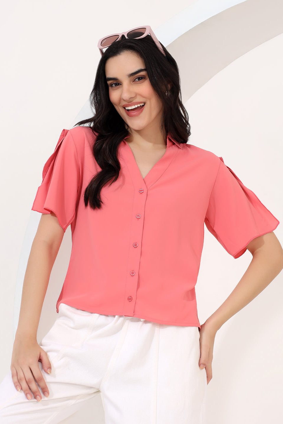 Woman wearing a pink blouse with ruffled sleeves on a white background