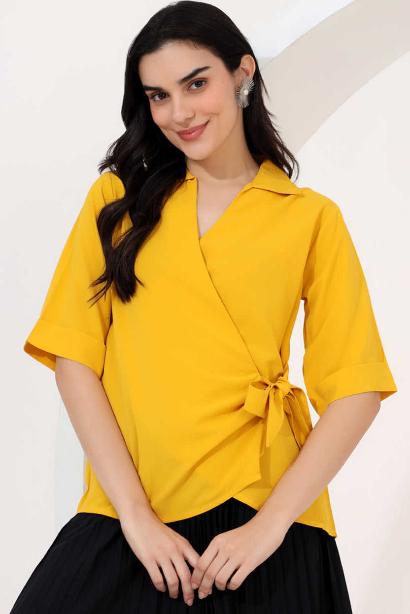 Woman wearing a yellow blouse with a tie detail on a white background