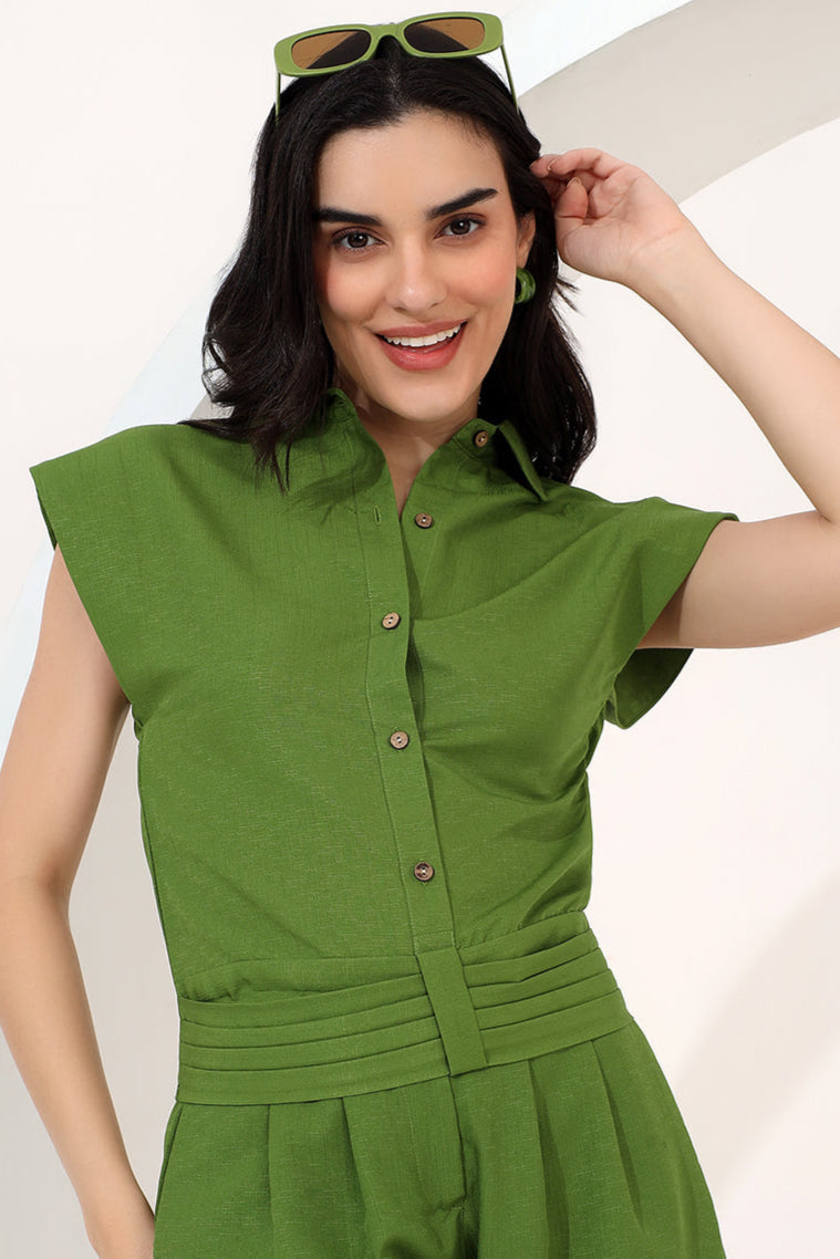 Woman wearing a green jumpsuit against a white background