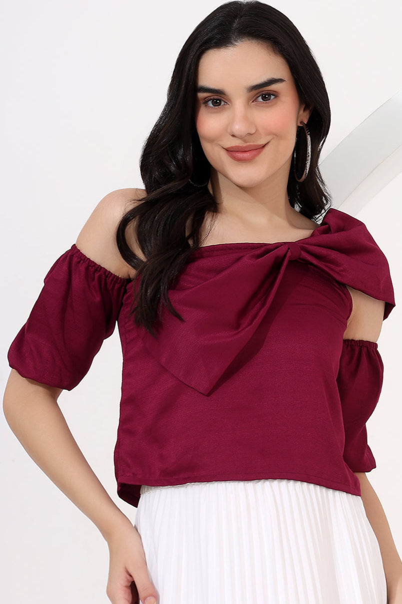 Woman wearing a burgundy off-shoulder top with a bow detail on a white background