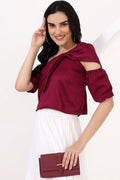 Woman wearing a burgundy top with cut-out design and holding a matching clutch against a white background