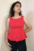 Woman wearing a red top and black pants on a plain background