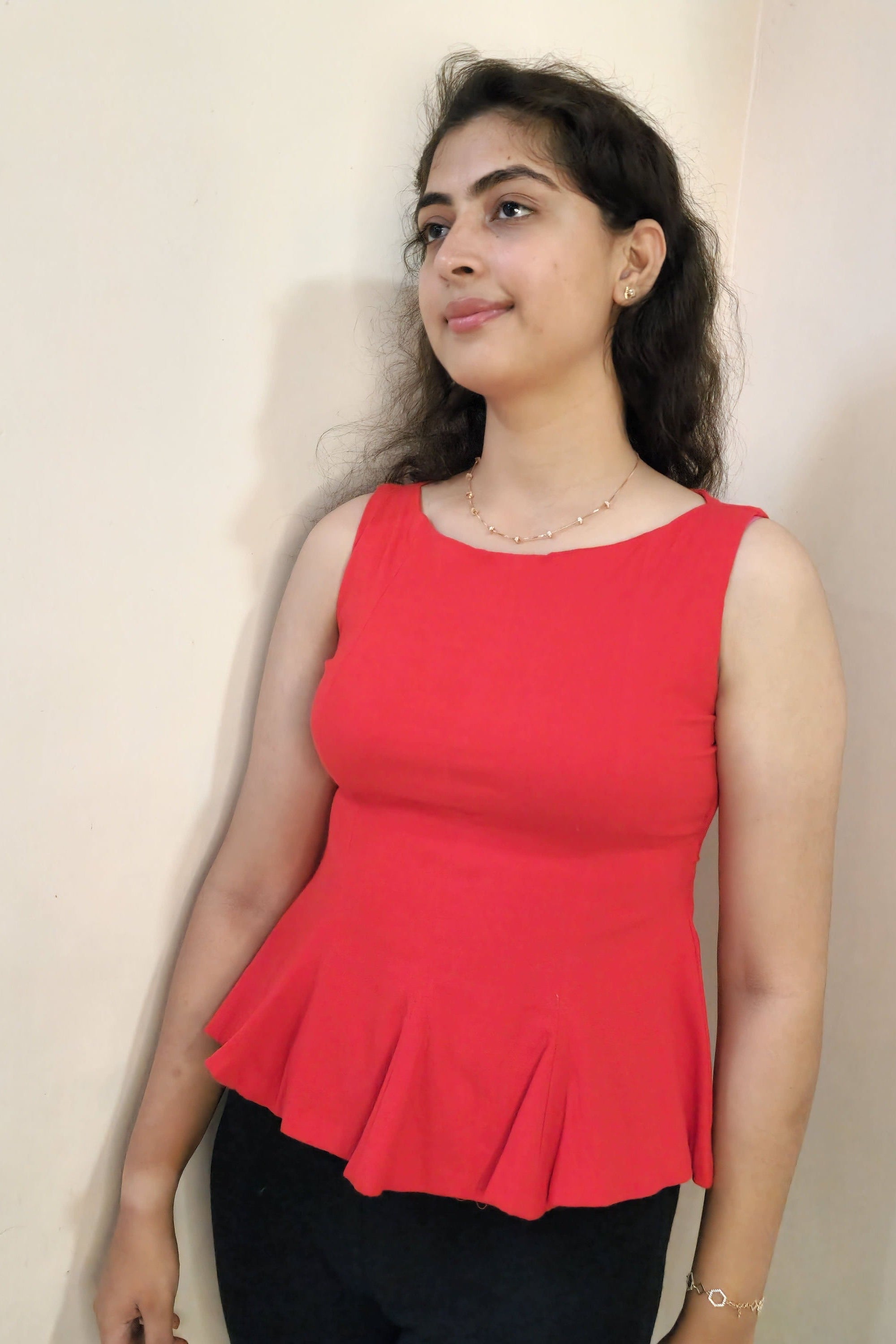 Woman wearing a red top and black pants on a white background