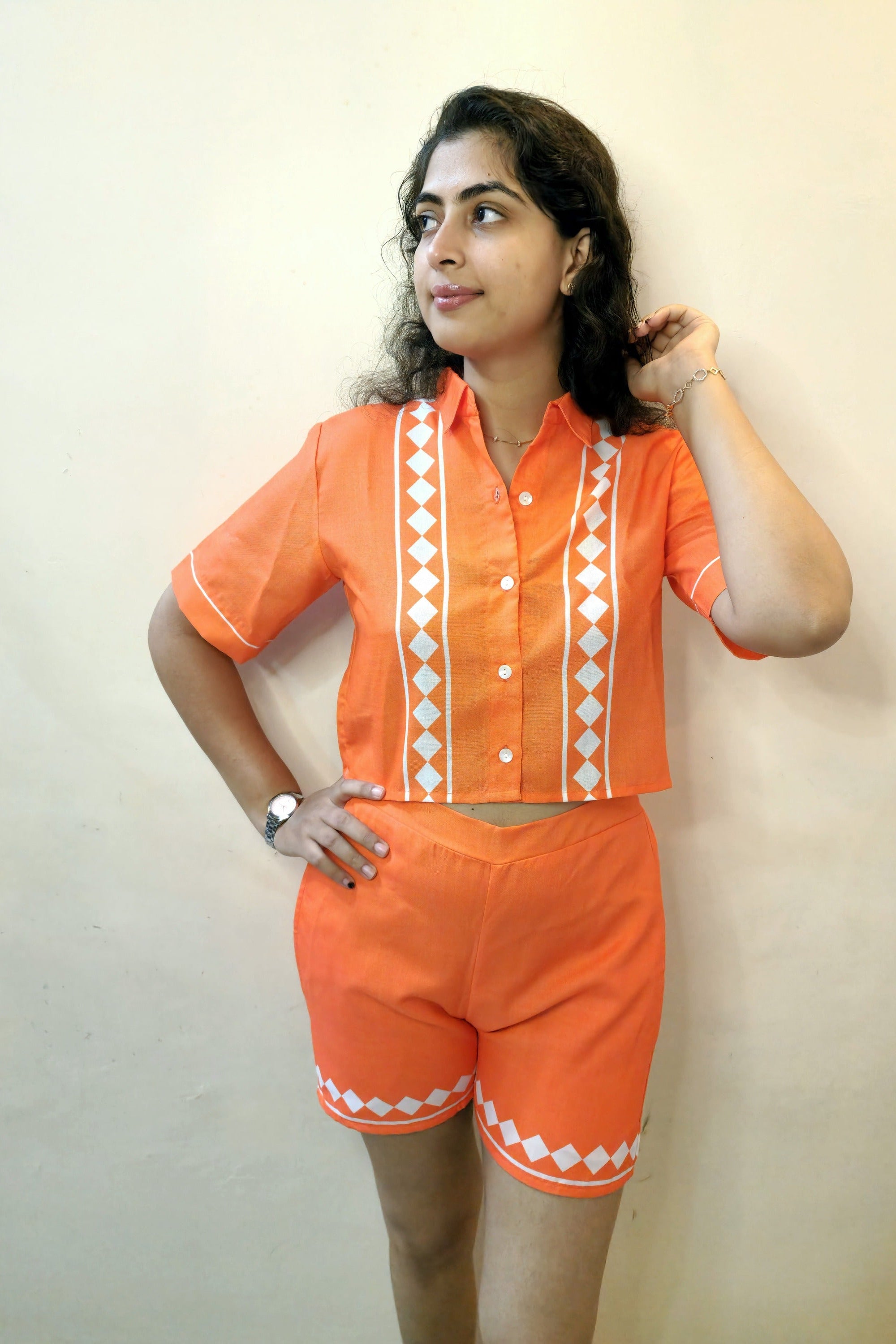 Woman wearing an orange outfit with white patterns against a plain background