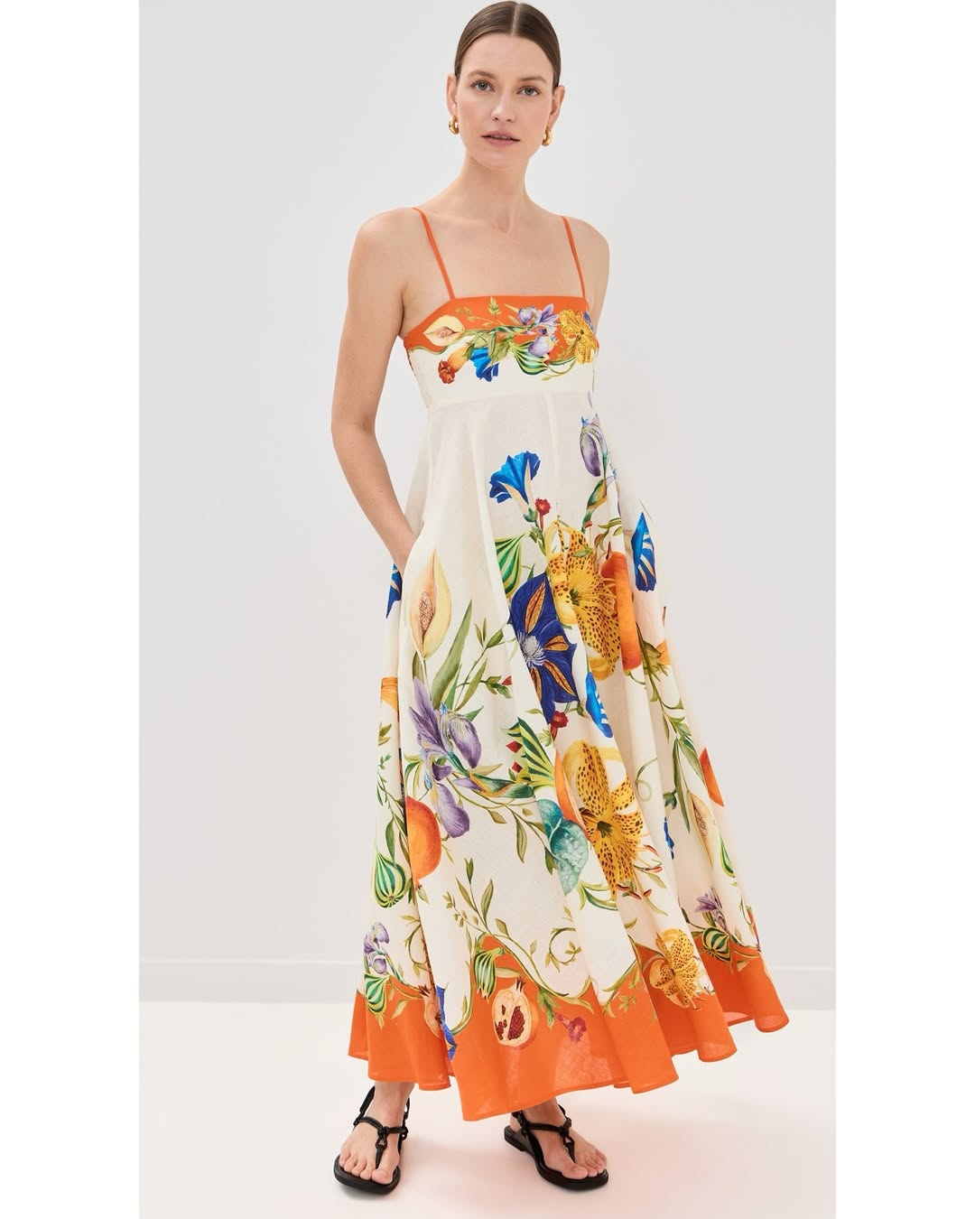 Woman wearing a floral dress with orange accents on a white background