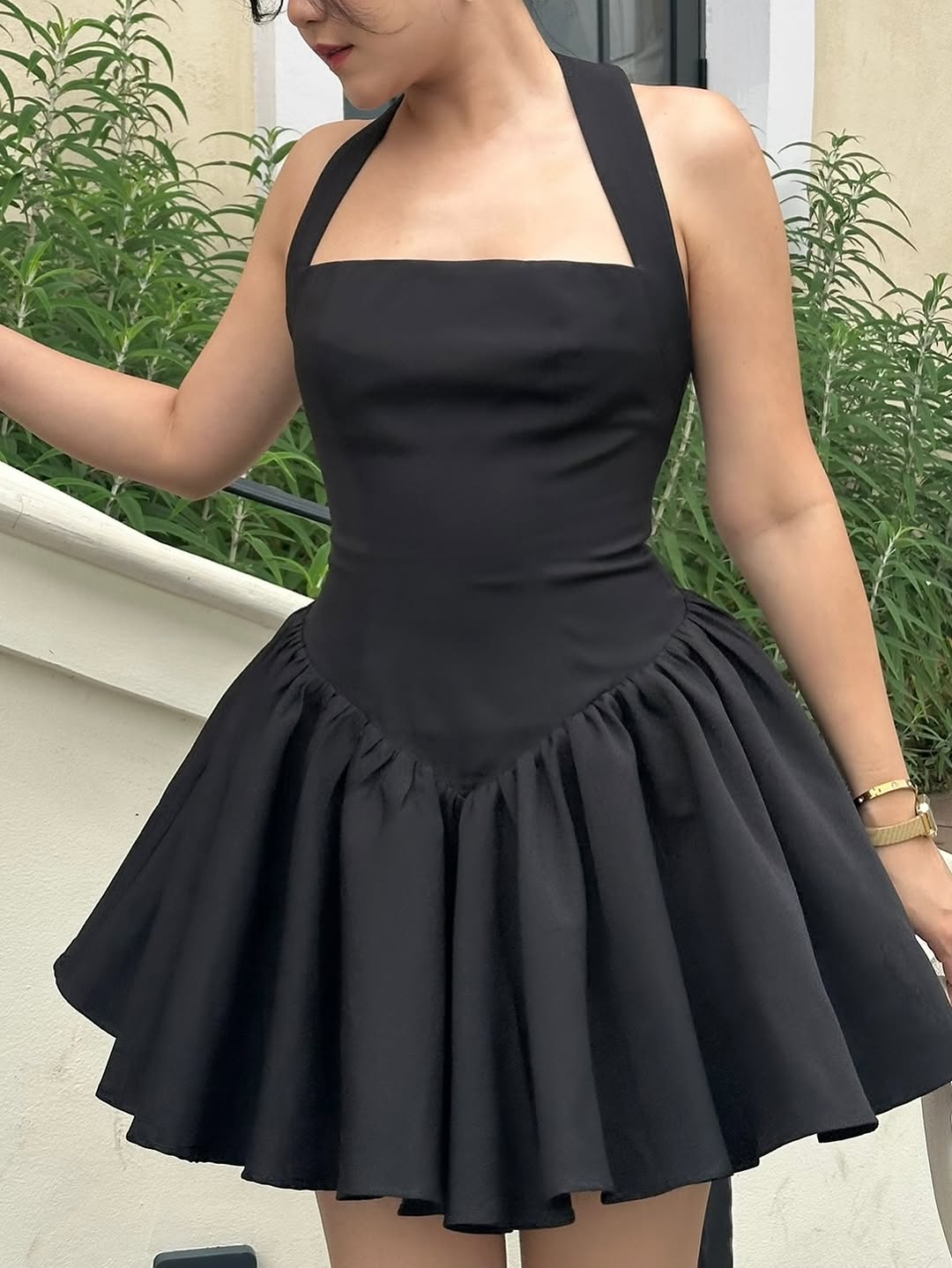 Woman wearing a black halter neck dress with a plain background