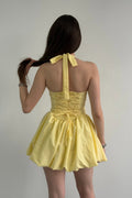Yellow dress with halter neck design on a plain background