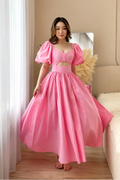 Woman in a pink dress standing in a room with a mirror and decorative elements.