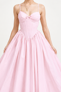 A woman modeling a light pink strapless midi dress with a sweetheart neckline, fitted corset-style bodice, and a full flared skirt, photographed against a plain light gray studio background.