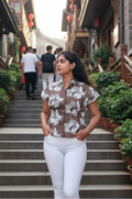 Woman standing on a set of stairs in an urban setting with traditional architecture and red lanterns.