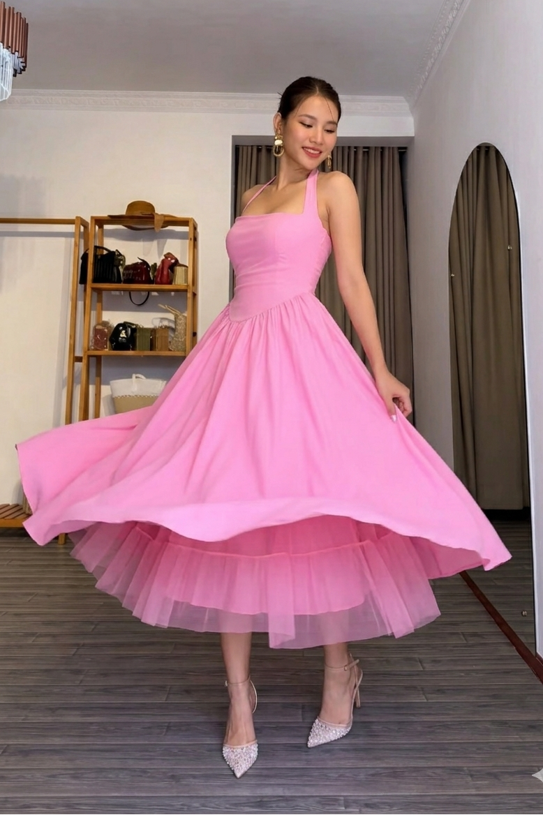 Woman in a pink dress standing in a room with wooden flooring and a shelf in the background.
