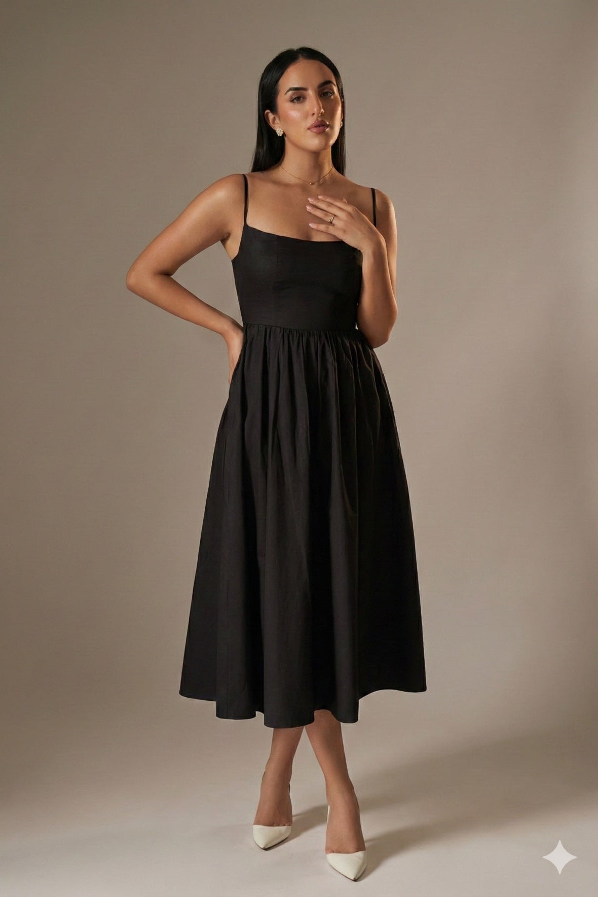 Woman wearing a black dress against a beige background