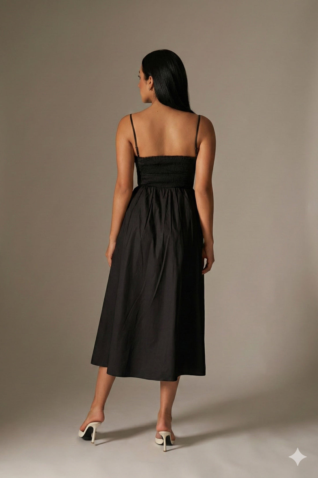 Woman wearing a black dress against a beige background