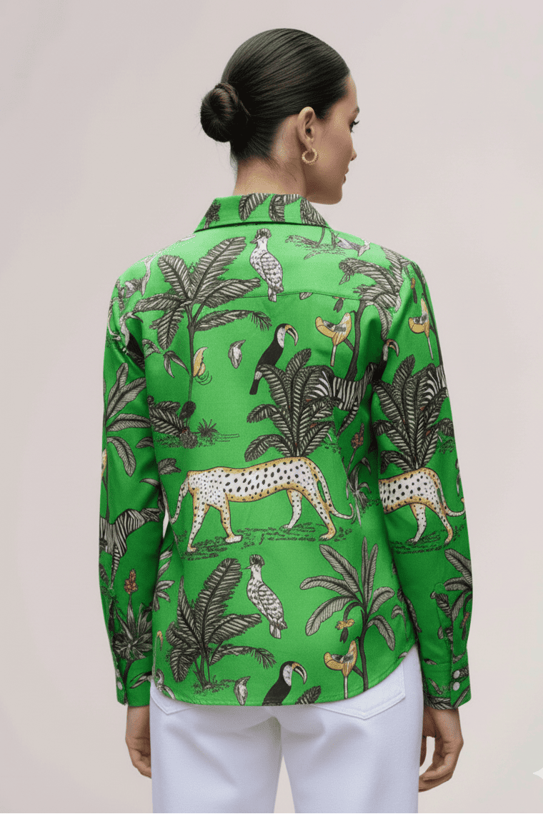 Woman wearing a green patterned shirt with white pants on a plain background