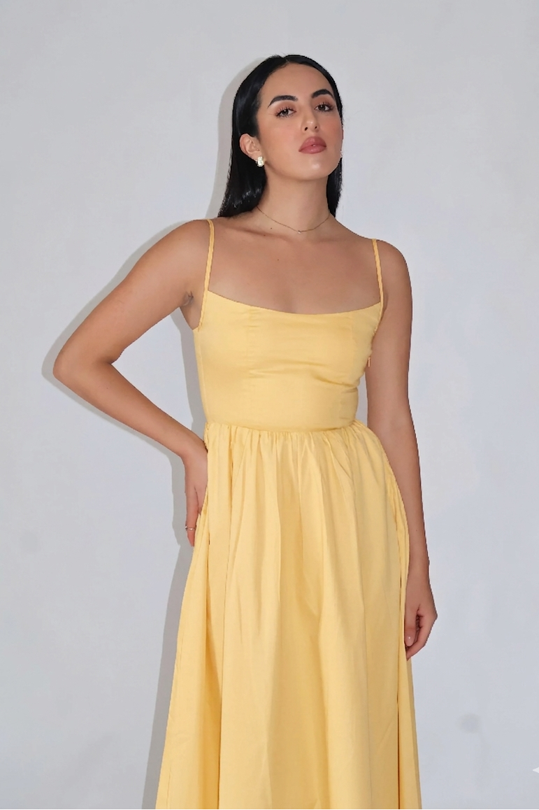Woman wearing a yellow dress against a plain background