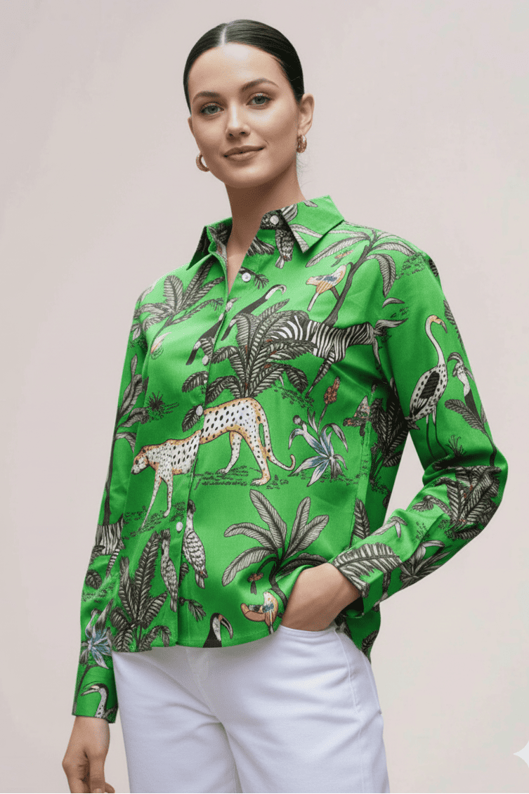 Woman wearing a green patterned shirt with white pants on a plain background