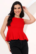 Woman wearing a red peplum top and black pants on a white background