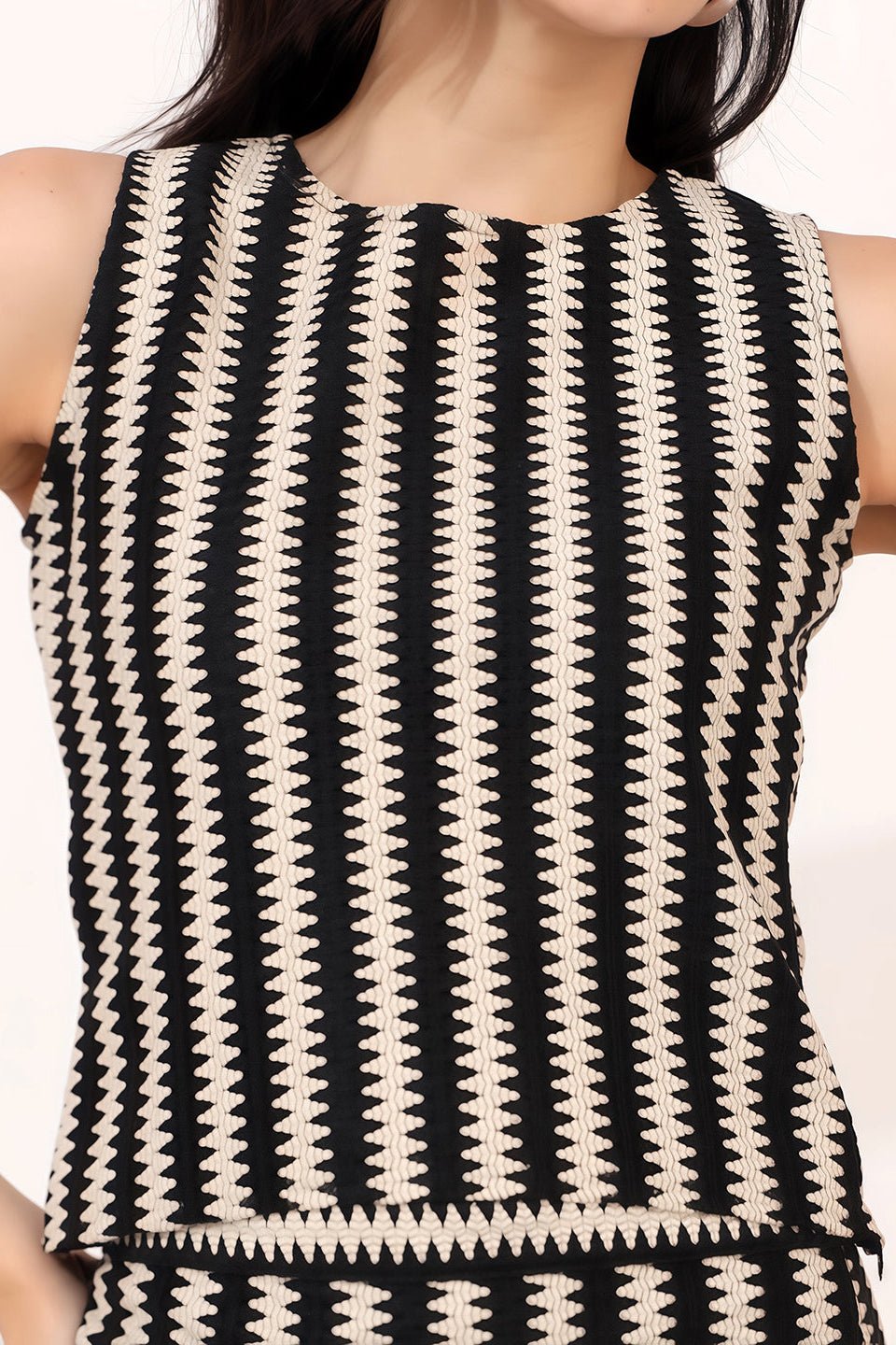 Black and white patterned sleeveless top worn by a person on a white background