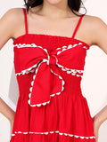 Red dress with white trim and bow detail on a plain background
