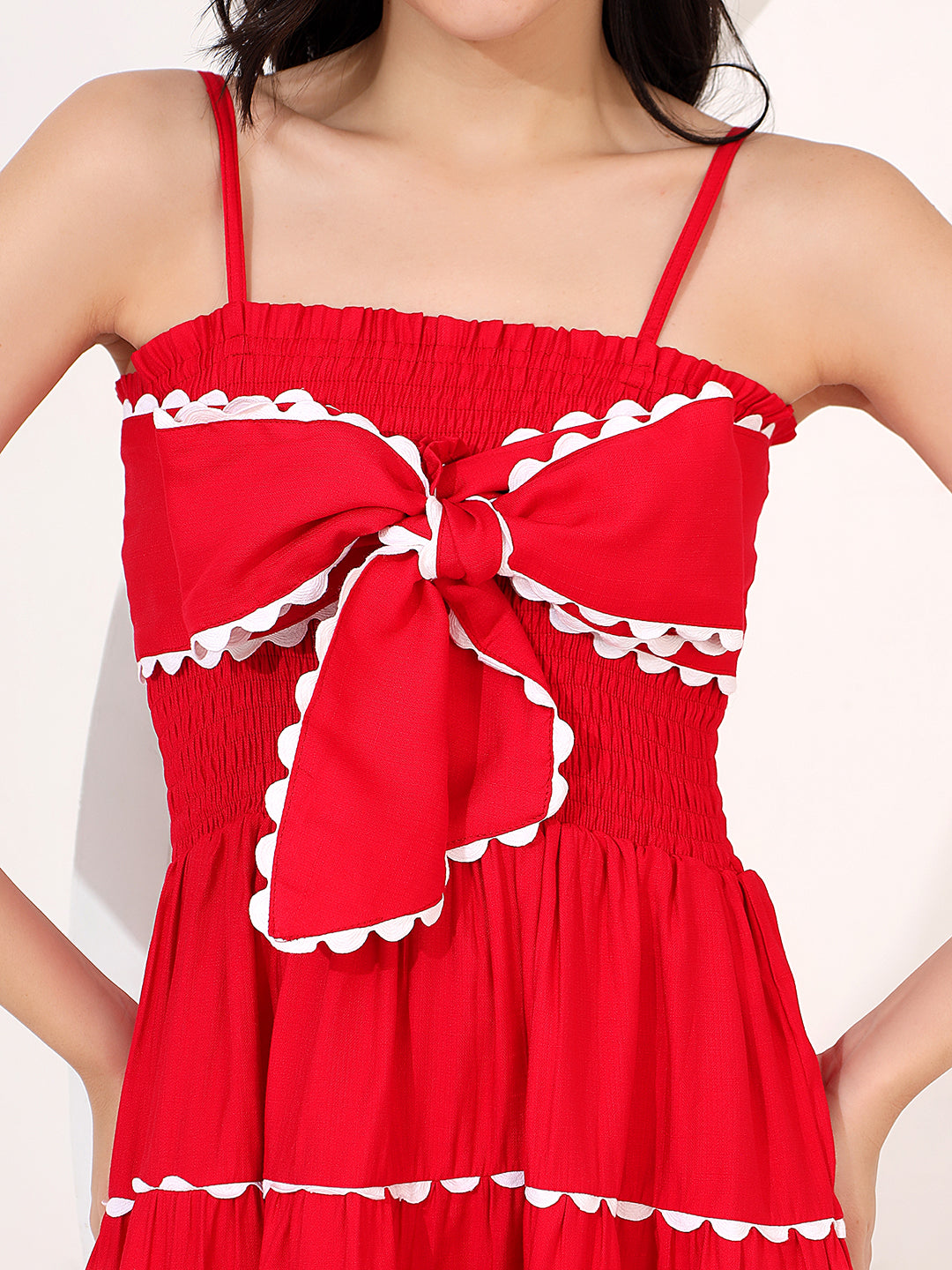 Red dress with white trim and bow detail on a plain background