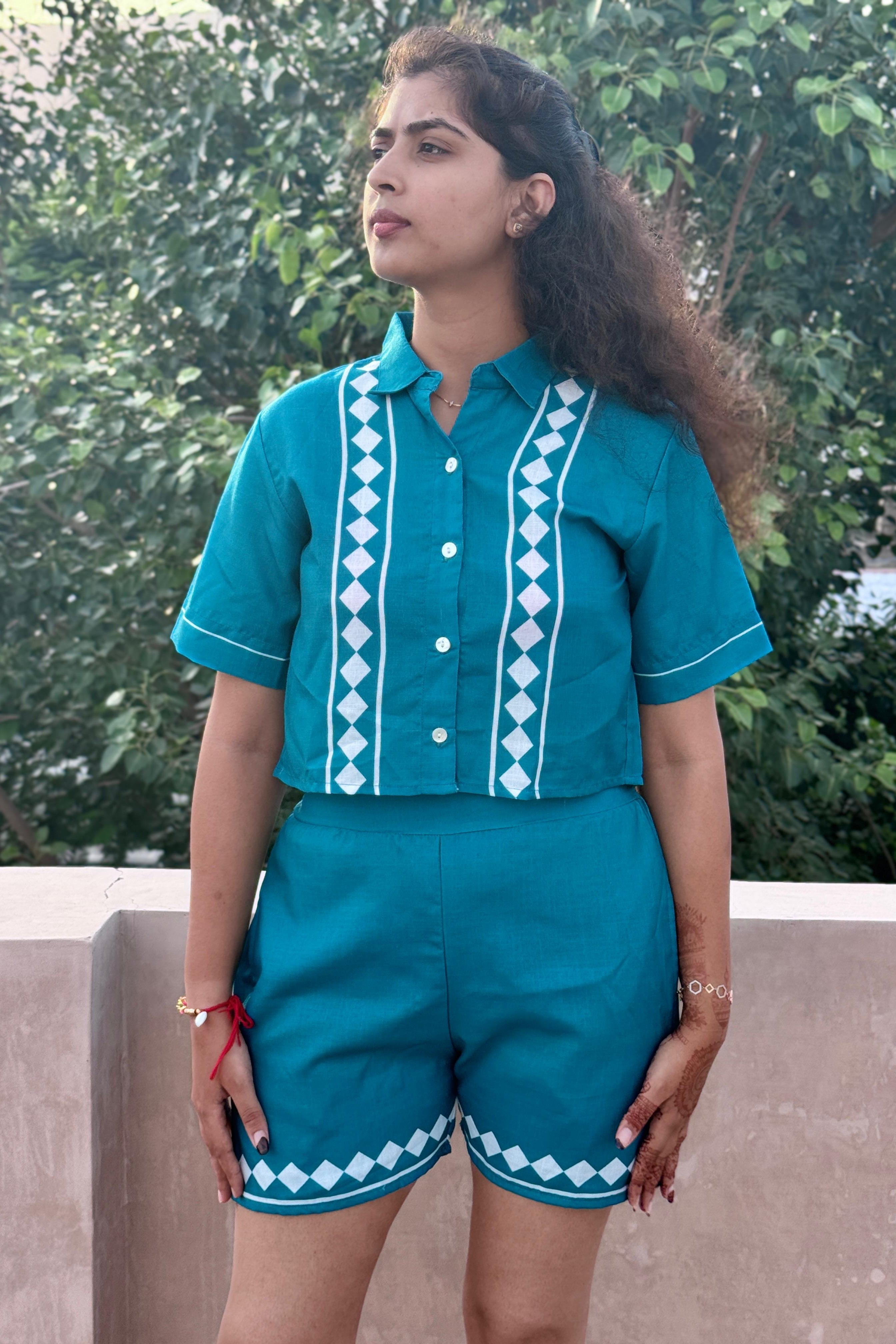 Woman wearing a teal outfit with white patterns outdoors