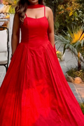 Red evening gown with thin straps worn by a person outdoors.