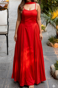 Woman in a red dress standing outdoors with plants and a path in the background