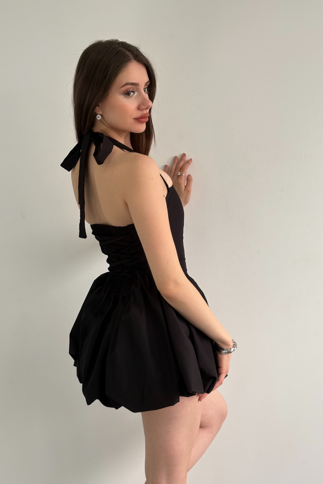 Woman wearing a black halter dress against a plain background