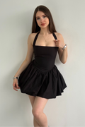 Woman wearing a black halter dress against a plain background
