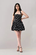 Woman wearing a black dress with white polka dots on a gray background