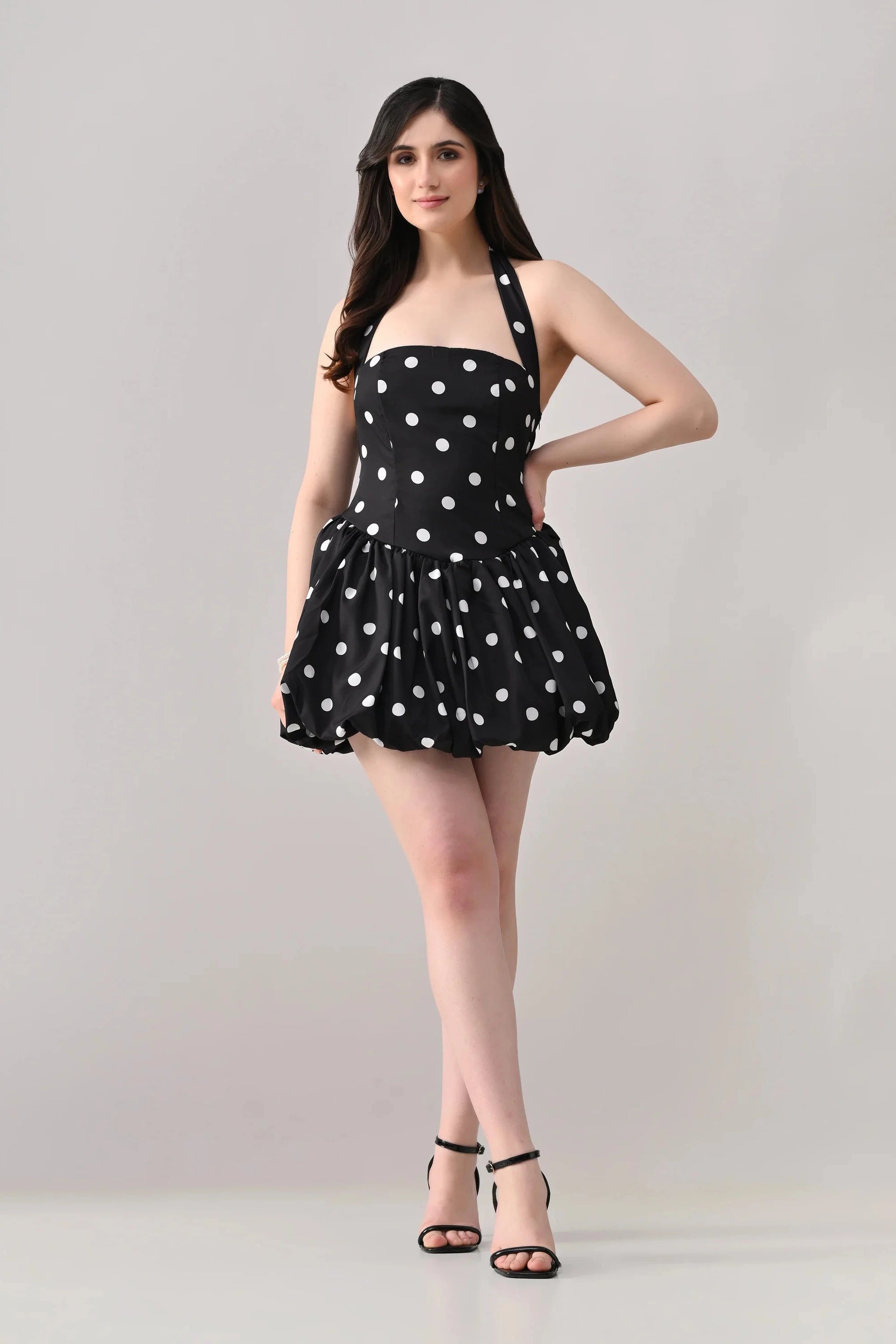 Woman wearing a black dress with white polka dots on a gray background