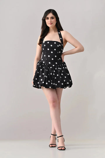 Woman wearing a black dress with white polka dots on a gray background
