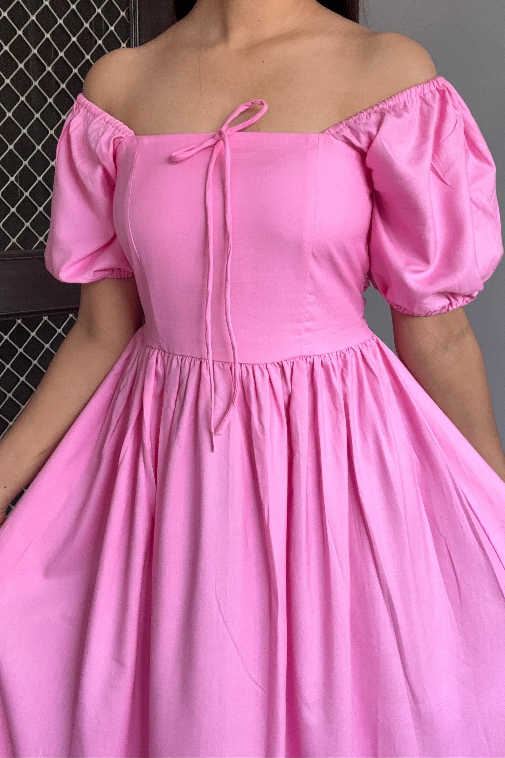 Woman wearing a pink off-shoulder dress with puff sleeves.