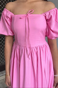 Pink off-shoulder dress worn by a person with a neutral background