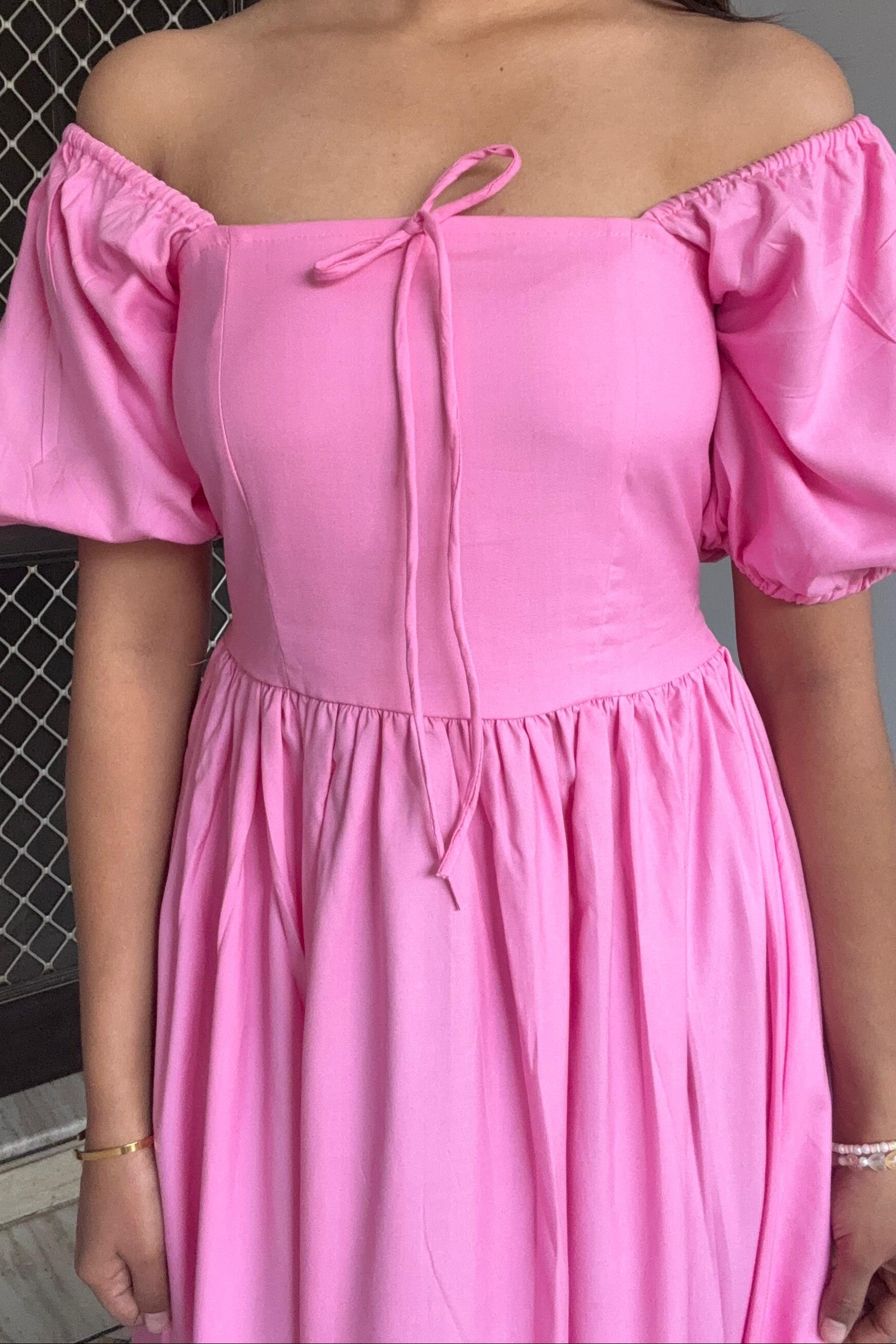 Pink off-shoulder dress worn by a person with a neutral background