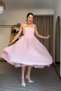 Woman in a pink dress posing in a room with a chandelier.