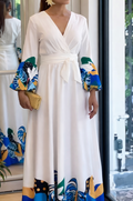 Woman in a white dress with colorful sleeves standing in front of a mirror.