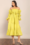 Woman wearing a yellow checkered dress with ruffled sleeves against a beige background