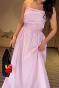 Woman in a pink dress holding a black handbag with flowers indoors.