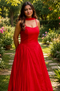 Woman in a red dress standing in a garden with flowers and greenery.
