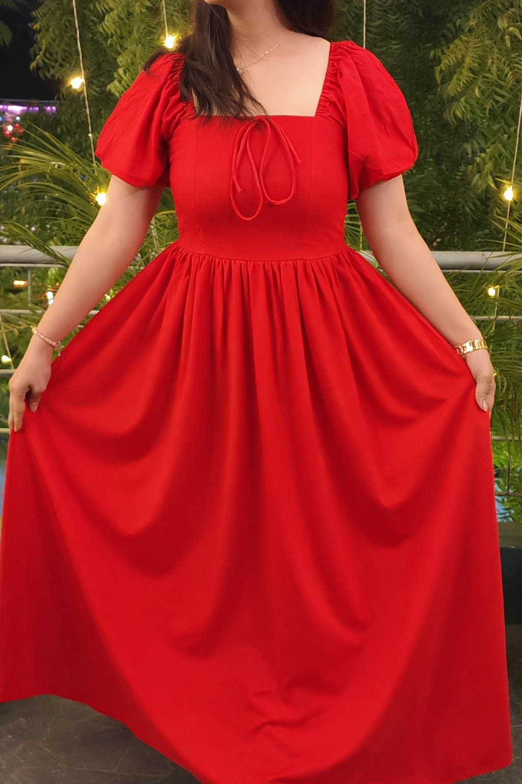 Red dress with puff sleeves worn by a person, with a blurred outdoor background.