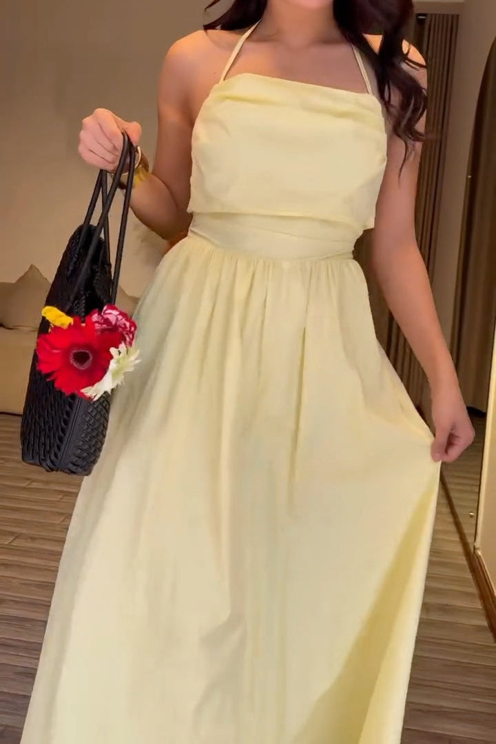 Woman in a yellow dress standing in a room with a couch and decorative pillows.