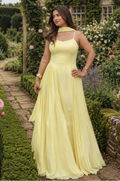 Woman in a yellow dress standing in a garden with a historic building in the background